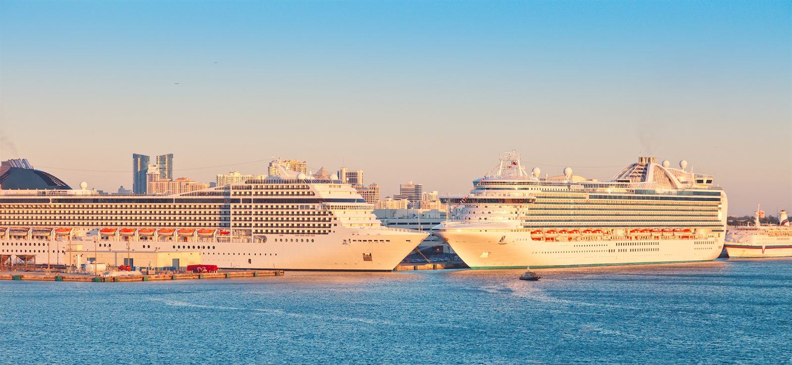 Two large cruise ships docked side by side at sunset